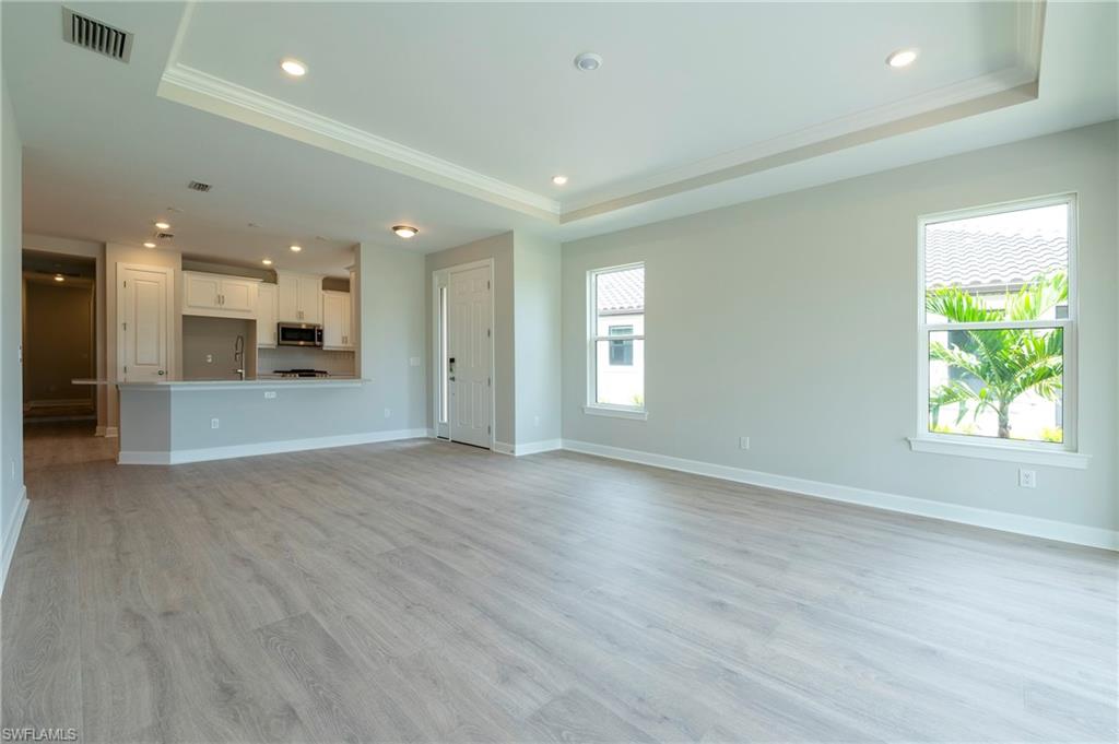 15633 Gavello Street Naples, FL 34114 - Photo 4 of 37 an empty room with wooden floor and windows