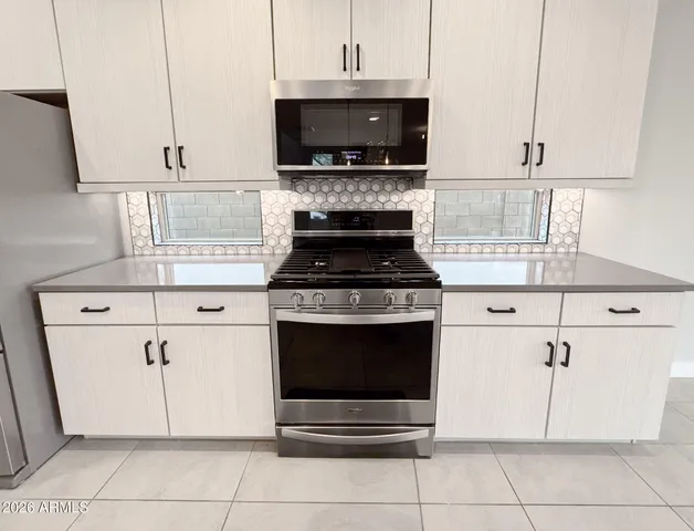 a large white kitchen with stainless steel appliances kitchen island granite countertop a large counter top a sink and a stove