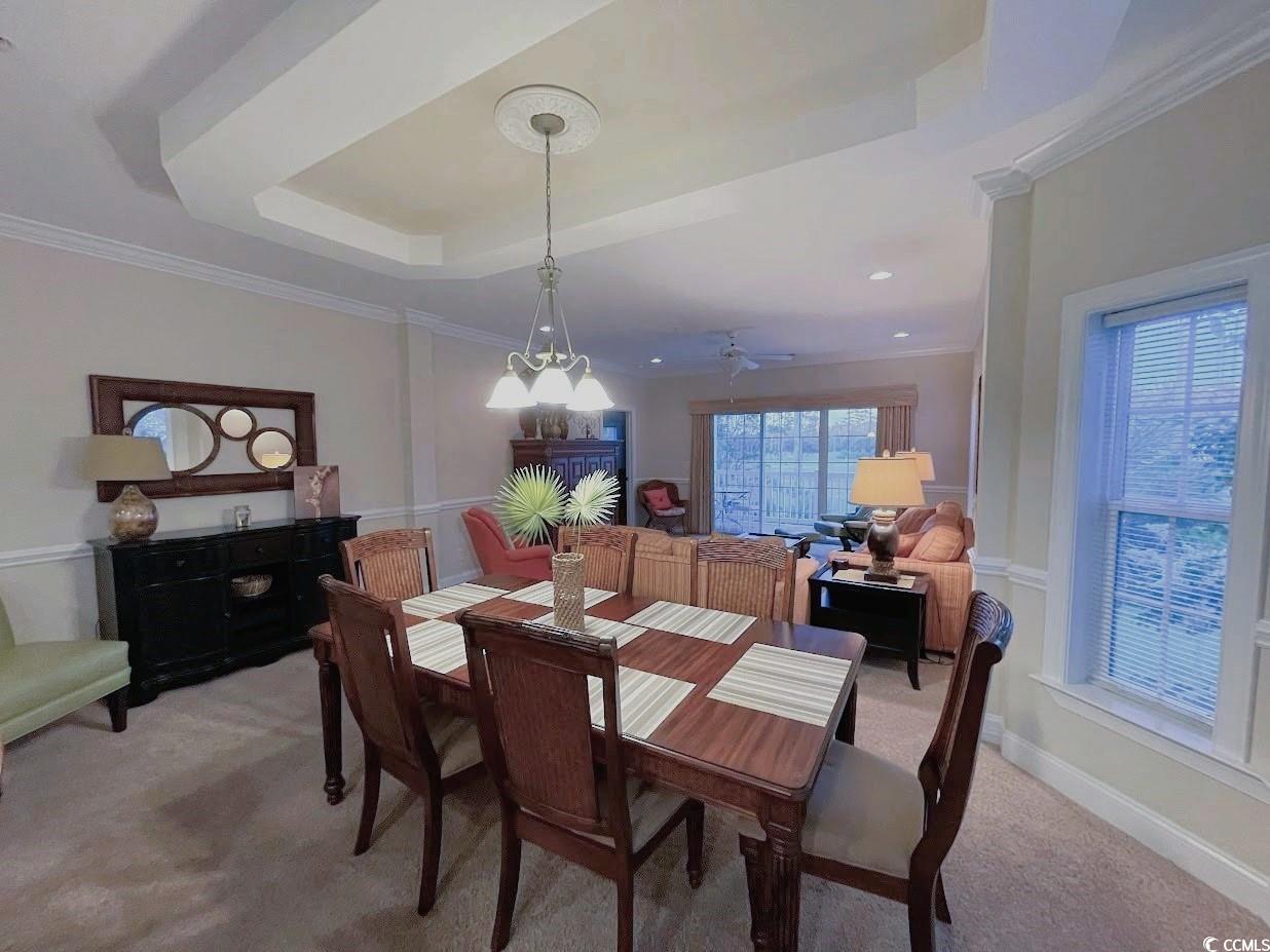 1008 Ray Costin Way, Unit 310 Murrells Inlet, SC 29576 - Photo 16 of 40 Dining area with ceiling fan with notable chandelier, light colored carpet, a raised ceiling, and ornamental molding