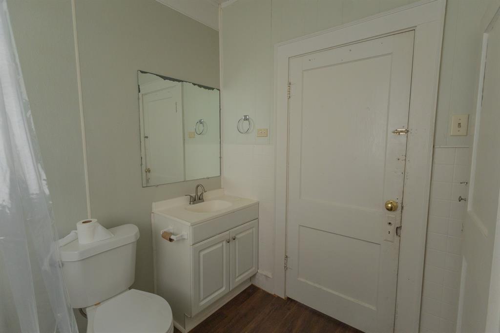 2913 Homan Avenue, Unit 2913 Waco, TX 76707 - Photo 8 of 16 Bathroom featuring a white vanity with integrated sink, chrome faucet, wall-mounted mirror, and wood-finish flooring