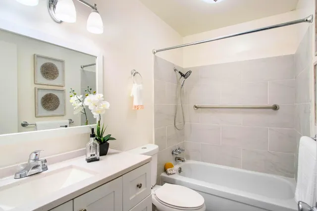 a bathroom with a granite countertop sink toilet a large mirror a shower and bathtub
