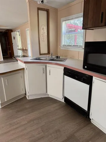 a view of a kitchen with a sink wooden cabinets and a window