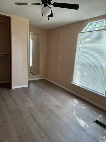 an empty room with wooden floor cabinet and windows