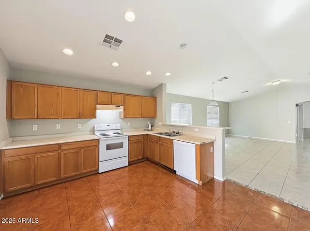 a large kitchen with a large counter top space a sink stainless steel appliances and cabinets