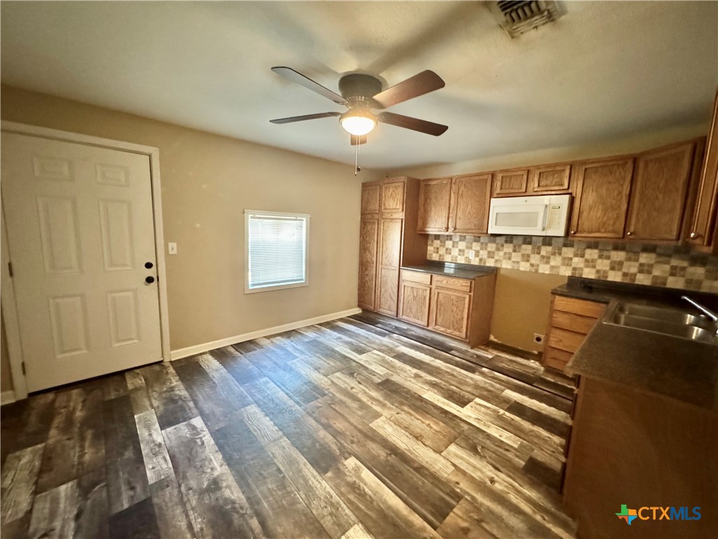 4904 Lone Tree Road Victoria, TX 77901 - Photo 4 of 13 a view of a kitchen with wooden floor and a ceiling fan