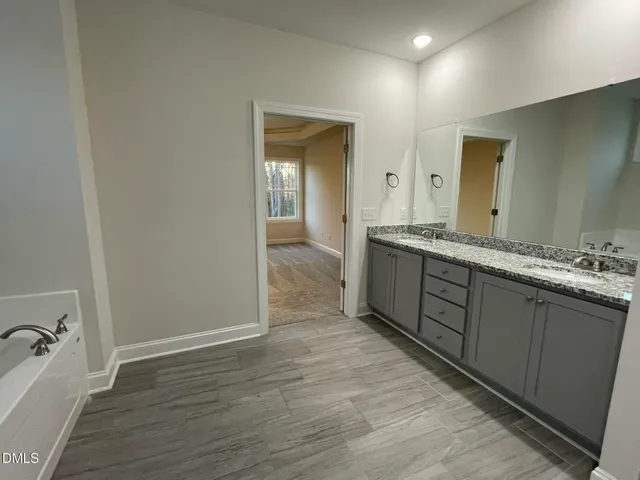 a bathroom with a granite countertop sink and a bathtub