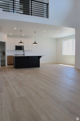 2613 Scarlet Road, Unit 258 Eagle Mountain, UT 84005 - Photo 7 of 32 Open-concept living area featuring light wood-finish flooring, a two-story ceiling, and a modern black railing on the upper level