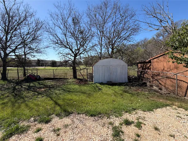 a backyard of a house with a large tree and wooden fence