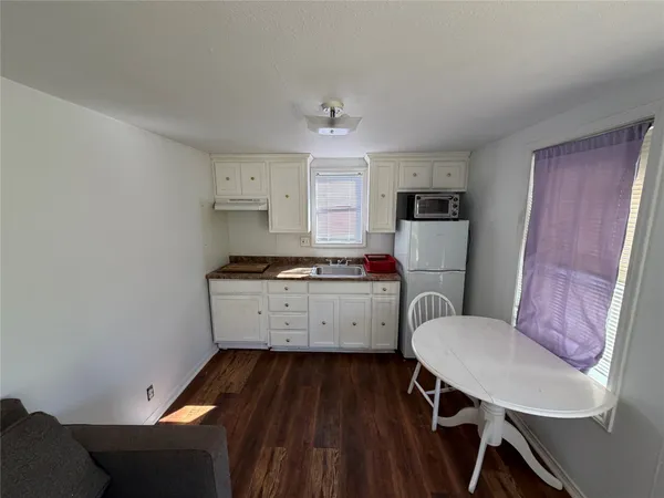 a kitchen with a refrigerator a stove a sink dishwasher and a dining table with wooden floor