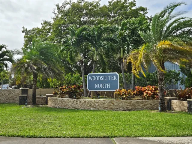 a view of a street with potted plants and large trees