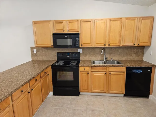 a kitchen with a sink a stove top oven a refrigerator and a microwave