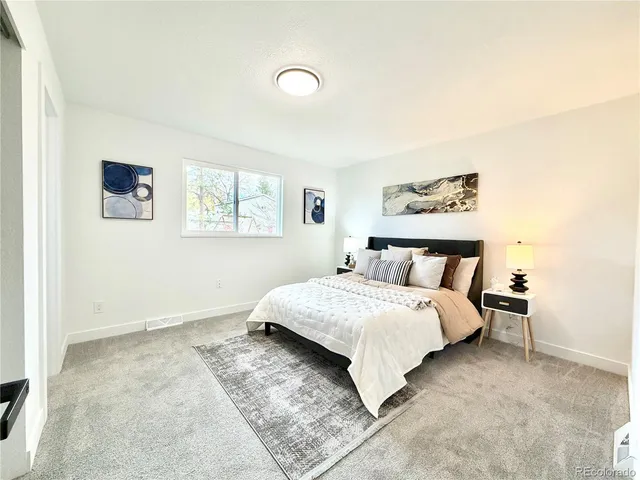 a spacious bedroom with a bed and a painting on the wall