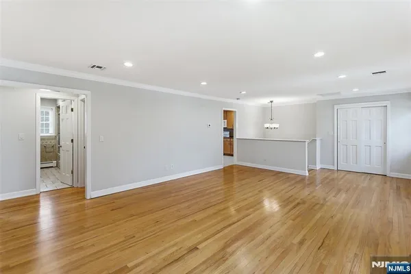 a view of empty room with wooden floor and kitchen