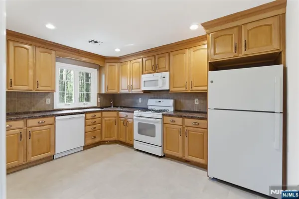 a kitchen with granite countertop cabinets stainless steel appliances a sink and a window