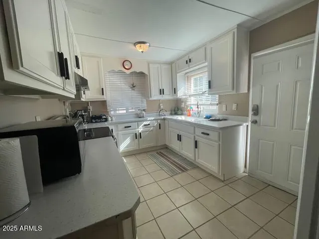 a kitchen with stainless steel appliances a sink a stove a refrigerator cabinets and a window