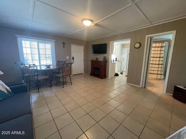 a living room with furniture a flat screen tv and a refrigerator