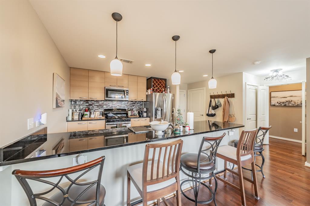 1200 Main Street, Unit 306 Dallas, TX 75202 - Photo 7 of 35 a kitchen with stainless steel appliances kitchen island granite countertop a dining table chairs and a refrigerator