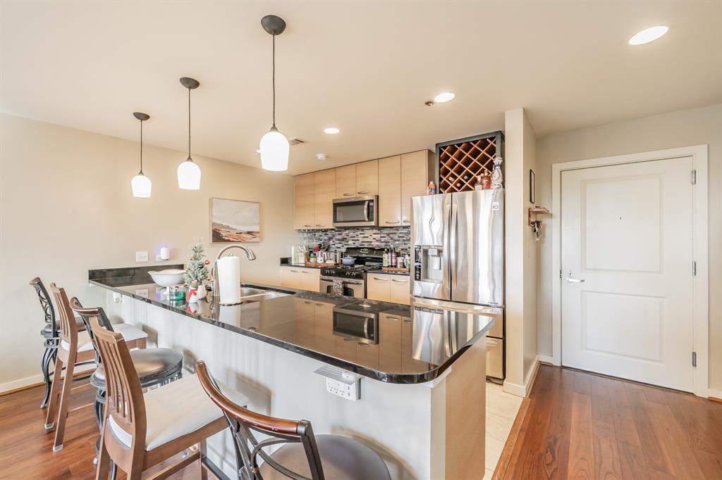 1200 Main Street, Unit 306 Dallas, TX 75202 - Photo 8 of 35 a kitchen with granite countertop a table chairs microwave and refrigerator