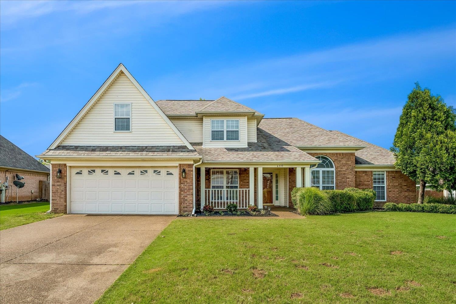 6335 Needle Ridge Road Bartlett, TN 38135 - Photo 1 of 25 Brick and siding exterior featuring a covered front porch with white railing, a two-car garage, and an arched window accent