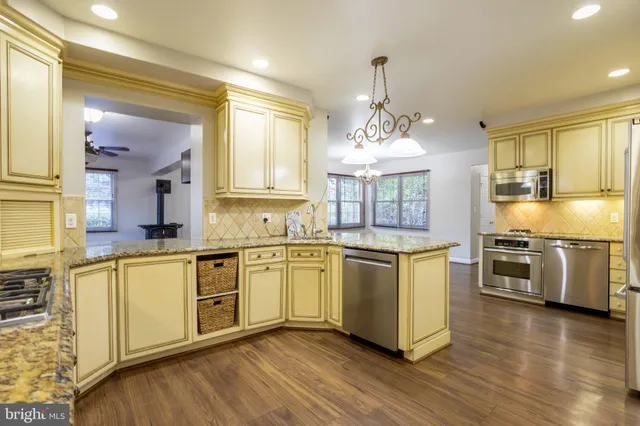 a kitchen with stainless steel appliances granite countertop a sink a stove and a wooden floors