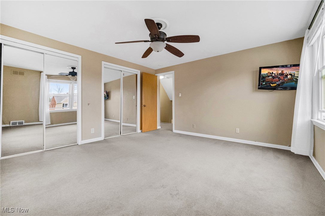 4430 Silsby Road Cleveland, OH 44118 - Photo 32 of 43 Unfurnished bedroom featuring ceiling fan, light carpet, and two closets