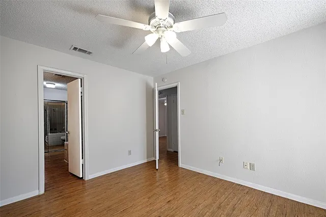 an empty room with wooden floor and ceiling fan