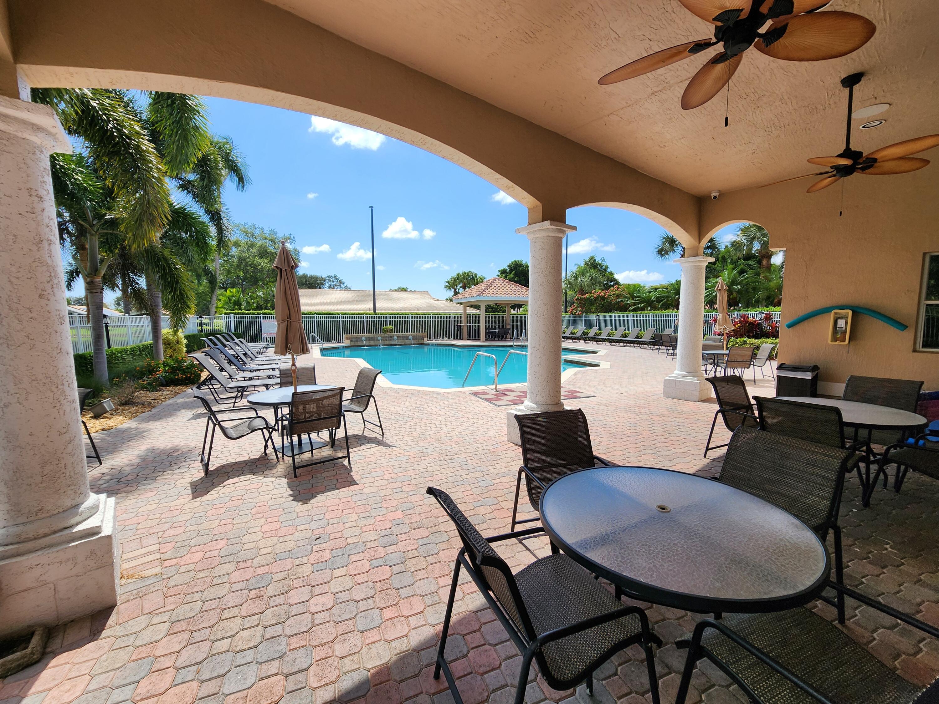 7316 Modena Drive Boynton Beach, FL 33437 - Photo 21 of 24 a view of a patio with a dining table and chairs with wooden floor and fence