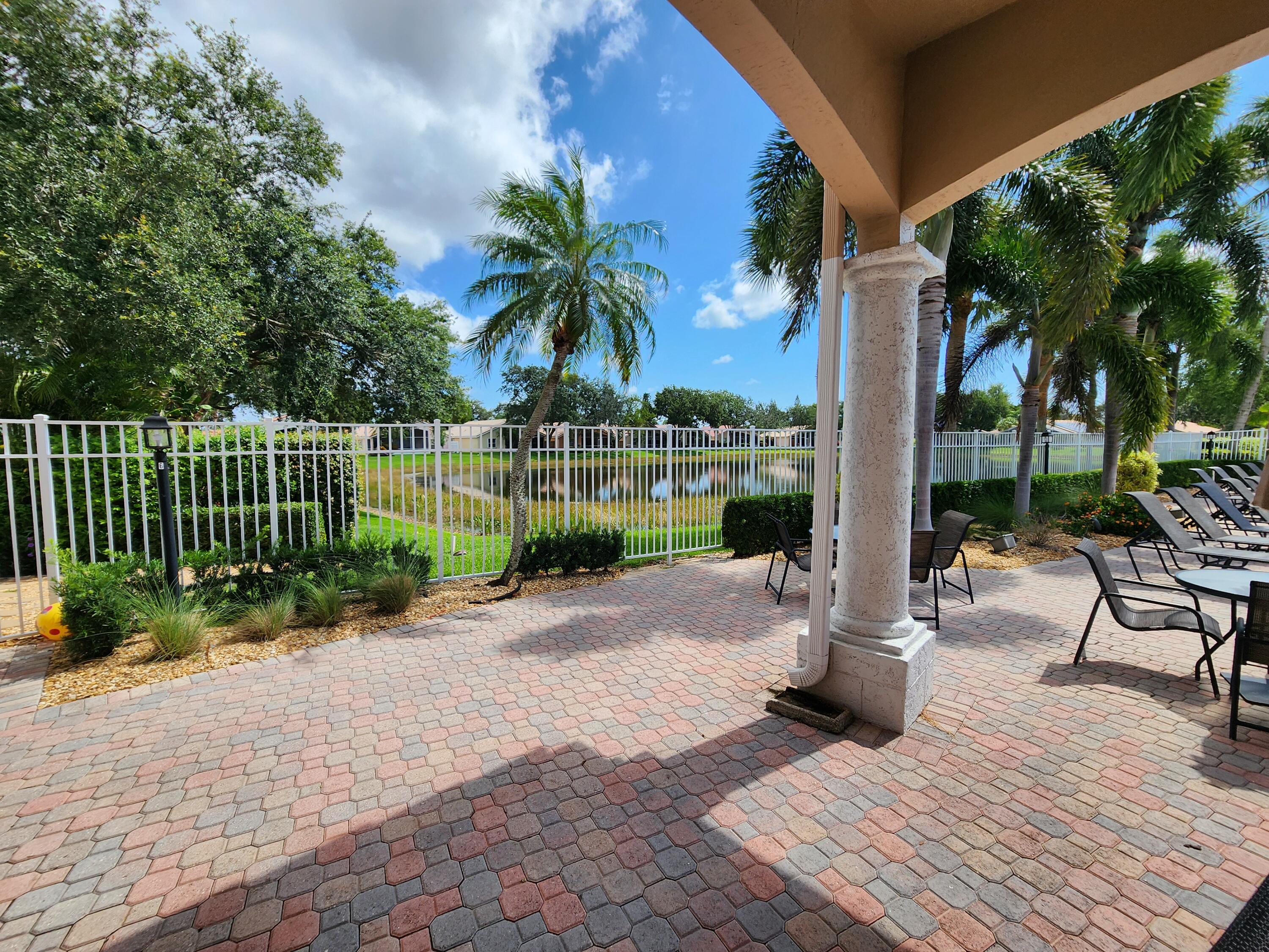 7316 Modena Drive Boynton Beach, FL 33437 - Photo 22 of 24 a view of a patio with table and chairs potted plants and palm trees