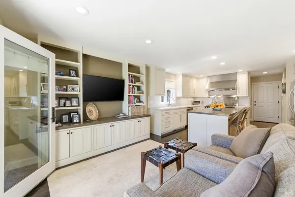 a living room with furniture a flat screen tv and kitchen view