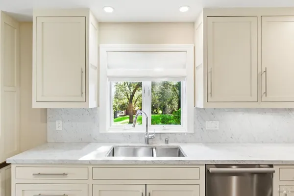a kitchen with granite countertop a sink window and cabinets