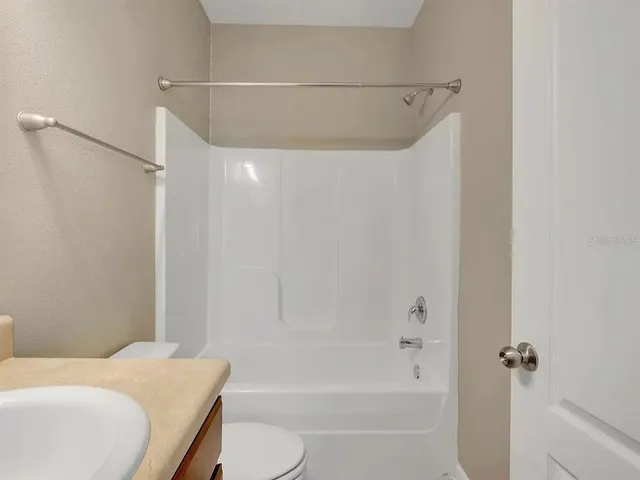 a bathroom with a granite countertop bathtub shower sink vanity and toilet
