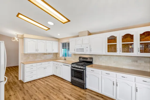 a kitchen with granite countertop white cabinets and white appliances
