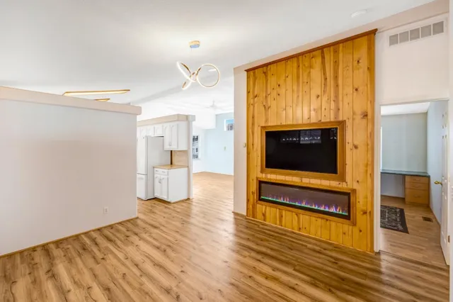 a view of a livingroom with wooden floor and a kitchen space