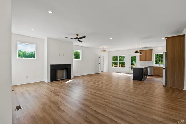 an empty room with wooden floor fireplace and windows