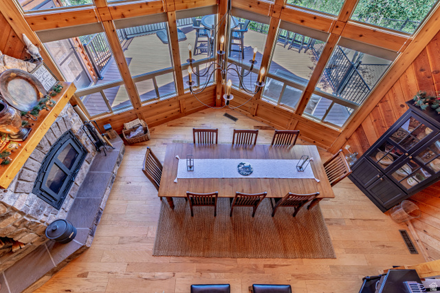 401 North Aoki Michi Road Brian Head, UT 84719 - Photo 14 of 58 Vaulted ceiling with exposed wood beams, expansive windows, wood-finish flooring, stone fireplace, and a chandelier