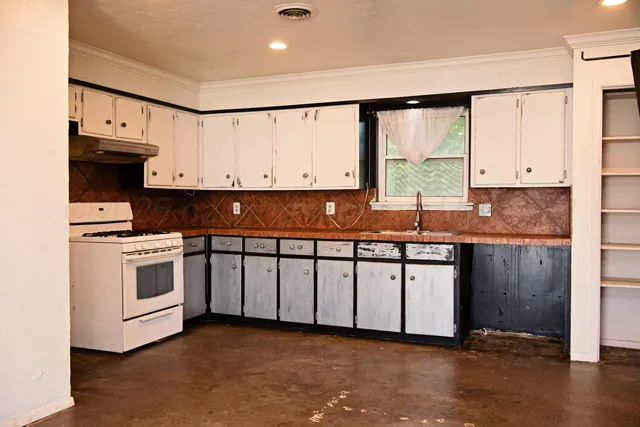 a kitchen with stainless steel appliances granite countertop a stove a sink and white cabinets