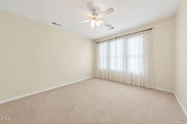 an empty room with chandelier fan and windows