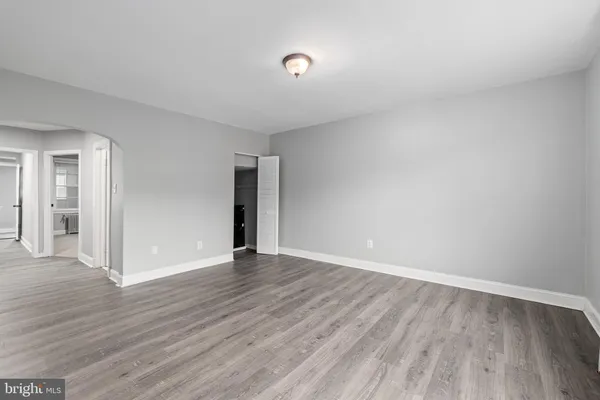 a view of an empty room with wooden floor and closet
