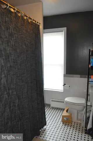 a bathroom with a toilet a window and shower