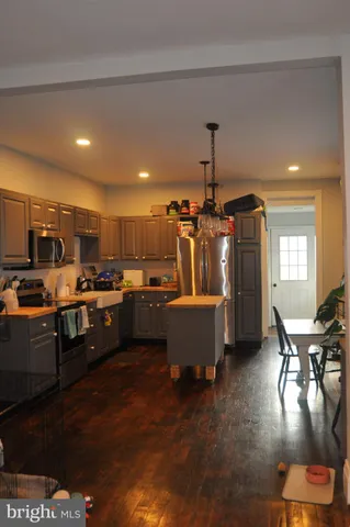 a kitchen with stainless steel appliances kitchen island granite countertop a stove a sink a refrigerator and blue cabinets with wooden floor