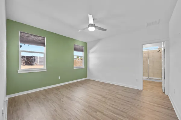 an empty room with wooden floor closet and windows