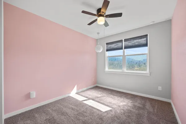 an empty room with a window and a fan