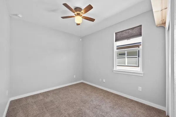 an empty room with a window and a ceiling fan