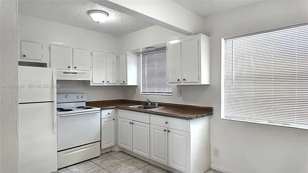 a kitchen with granite countertop white cabinets and white appliances