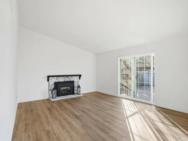 a view of empty room with wooden floor and fireplace