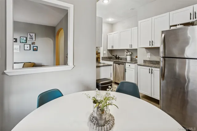 a kitchen with stainless steel appliances a refrigerator a stove a sink a dining table and chairs