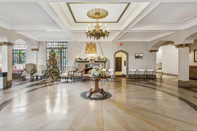 a living room with fireplace chandelier and kitchen view