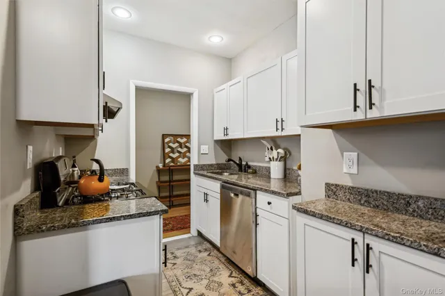 a kitchen with granite countertop a sink stove and cabinets