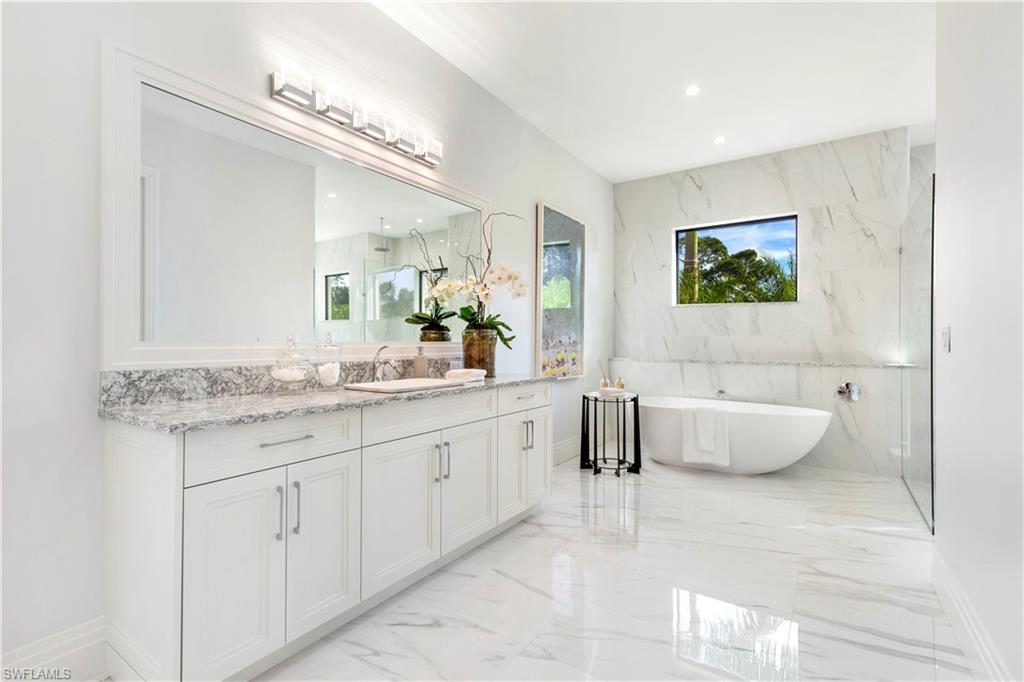 437 West Street Naples, FL 34108 - Photo 18 of 35 a spacious bathroom with a granite countertop tub sink and mirror
