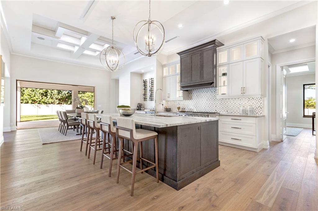 437 West Street Naples, FL 34108 - Photo 6 of 35 a kitchen with stainless steel appliances granite countertop a stove a sink dishwasher a dining table and chairs with wooden floor